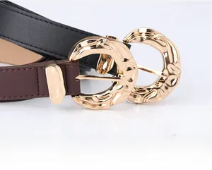 Close-up of wide faux leather belts featuring oversized gold-tone hammered metal buckles