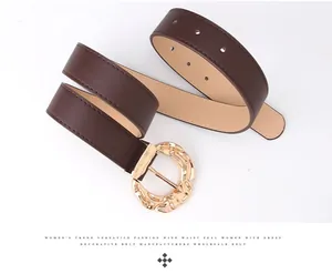 Detail of wide brown leather belt featuring a textured irregular gold metal buckle