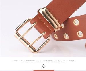Close-up of brown leather belt with golden double prong buckle and metal eyelets