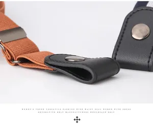 Detail of brown elastic belt with black leather end and silver metal snap button closure