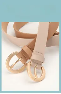 Détails rapprochés de ceintures en cuir marron et beige avec boucles dorées rondes