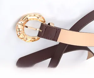 Macro shot of stylish brown faux leather belt featuring a chunky irregular gold buckle
