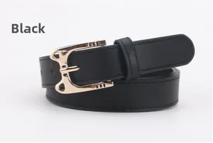 Detail of a thin black leather belt featuring a golden bow-shaped alloy buckle closure