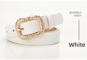 Detail of white leather belt showing golden buckle with embossed floral pattern engraving