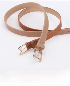 Close-up of golden hollow cat-shaped buckles on slim brown and beige leather belts