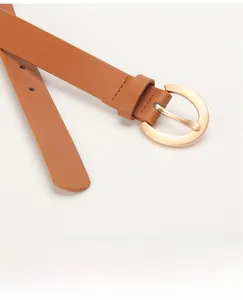 Gros plan détaillé de la ceinture en cuir marron avec une boucle ronde dorée élégante
