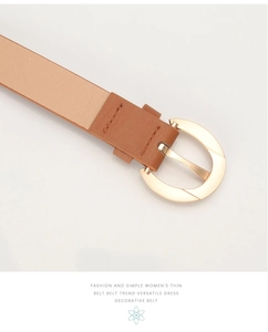 Gros plan d'une ceinture fine en cuir camel avec une boucle métallique ovale dorée