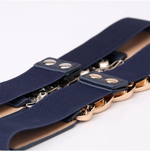 Vue macro de la ceinture élastique bleu marine avec chaîne dorée et boutons pressions
