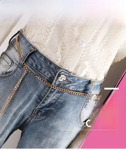 Close-up of a stylish gold metal chain belt with lobster clasp on blue denim jeans