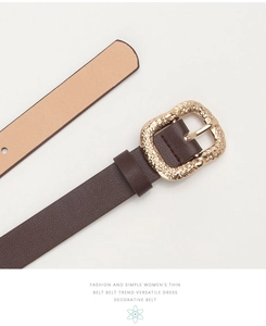 Close-up of a slim coffee brown leather belt with a vintage engraved gold alloy buckle