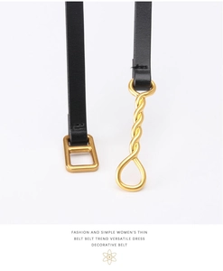 Detail of slim black leather belt featuring unique gold hardware and twisted buckle