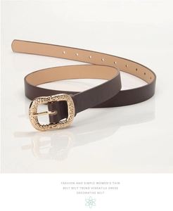 Detail of slim brown leather belt featuring a vintage gold embossed buckle on white background