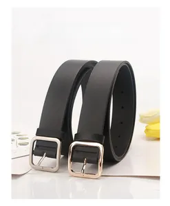 Close-up of minimalist black leather belts with gold and silver square metal buckles