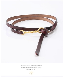Detailed macro view of slim red-brown leather belt featuring a gold twisted metal buckle