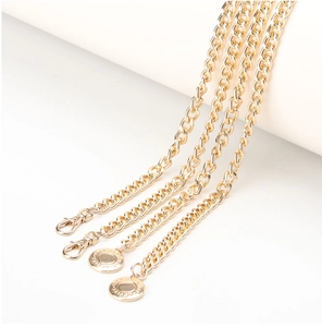 Detail of four-layered gold metal waist chains featuring lobster clasps and engraved pendants
