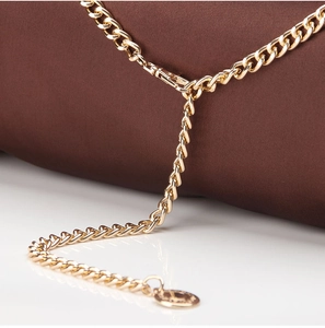 Detail of a golden metal chain with lobster clasp and decorative round charm