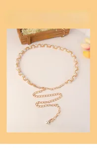 Détail d'une élégante chaîne de taille dorée avec perles blanches et fermoir mousqueton