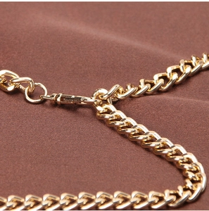 Detailed close-up of golden metal curb chain belt with high-gloss finish and lobster clasp
