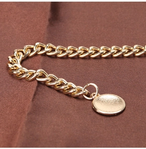 Detailed close-up of golden metal Cuban chain links with a polished round flat pendant