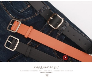 Close-up of black and caramel leather fashion belts with square metal buckles on denim pants