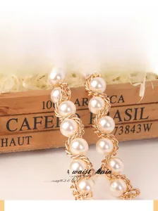 Détail d'une chaîne de taille élégante avec perles blanches et chaîne en métal doré