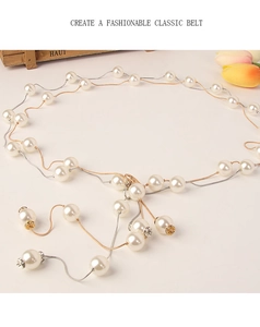 Dettaglio di elegante catena dorata per la vita con perle bianche e accenti di strass