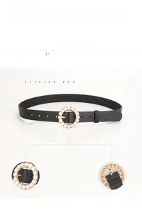 Close-up detail of black leather belt with circular buckle featuring embedded white pearls