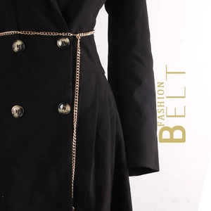 Minimalist gold metal chain belt with long decorative drop on a black suit jacket