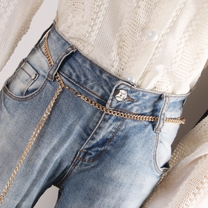Chic gold-toned alloy metal chain waist belt accessory styled on blue denim jeans