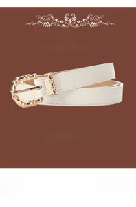 Close-up of white PU leather belt with golden bamboo-style buckle on brown background