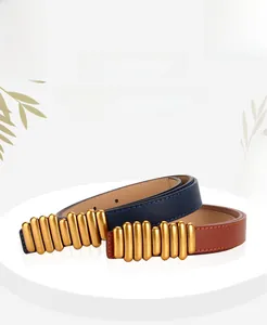 Dettaglio di sottili cinture in pelle con fibbie dorate a tubi in blu navy e marrone