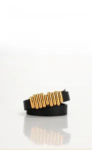 Dettaglio della cintura da donna in pelle nera con fibbia dorata vintage a righe