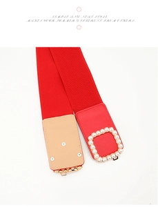 Dettaglio di una cintura elastica rossa con fibbia quadrata e decorazione di perle