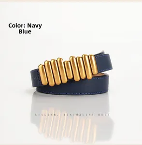 Dettaglio della cintura sottile blu navy con fibbia a coste dorata su fondo grigio