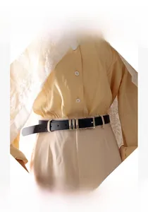 Detail of minimalist black leather belt with rectangular pin buckle on a yellow shirt