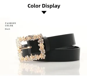 Close-up of golden square belt buckle with rhinestones and rose flower on black leather