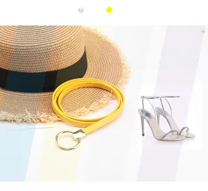 Gelber schmaler Gürtel mit goldener Rundschnalle und modischen Sommeraccessoires