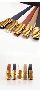 Dettaglio della fibbia dorata minimalista e delle cinque cinture in pelle di diversi colori