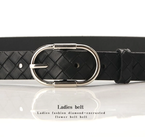 Détail d'une ceinture en cuir tressé noir avec une boucle ovale en métal argenté poli
