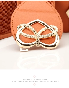 Detail eines orangen elastischen Taillengürtels mit goldener Schleifenschnalle und Webstruktur