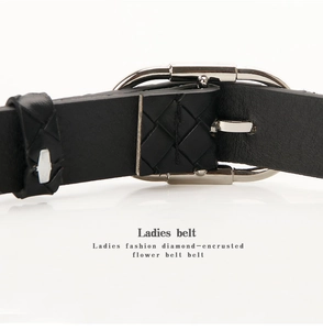 Détail de ceinture en cuir noir pour femme avec boucle argentée et texture tressée élégante