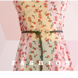 Détail de la ceinture tressée vert foncé avec boucle dorée sur robe à fleurs
