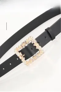 Detail of elegant black belt featuring a square alloy buckle with rhinestones and floral relief