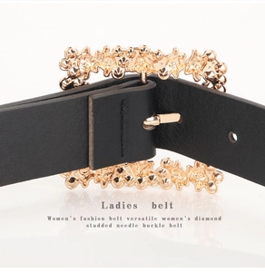 Detail of elegant gold rhinestone buckle on premium black leather belt for women