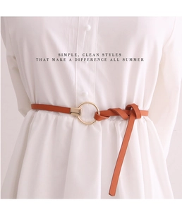 Detail eines karamellfarbenen Ledergürtels mit goldener Schnalle, geknotet am Kleid