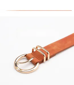 Detailed macro view of the gold alloy buckle and orange leather texture on the belt