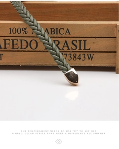 Détail de la ceinture tressée main vert olive avec une boucle dorée en forme de gouttelette