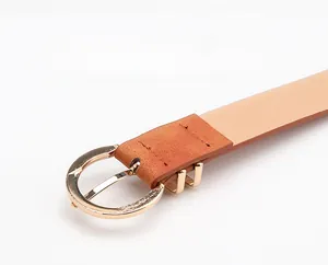 Detail of caramel brown leather belt with round golden alloy buckle and neat stitching