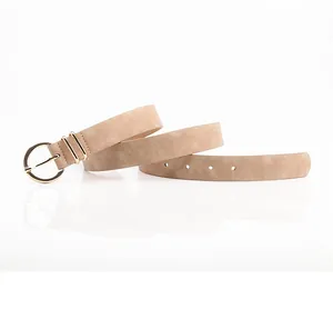 Detail view of a beige leather belt with a polished gold circular metal buckle