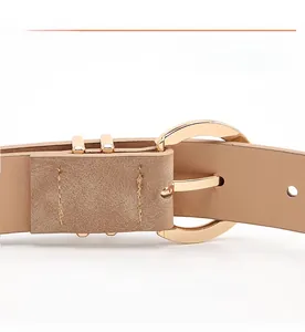 Detail of light brown leather belt with gold round buckle and precise double stitching